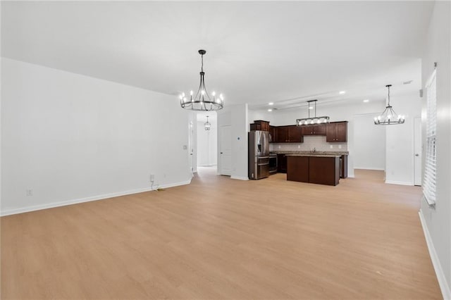 kitchen featuring stainless steel refrigerator with ice dispenser, hanging light fixtures, decorative backsplash, a kitchen island, and a chandelier