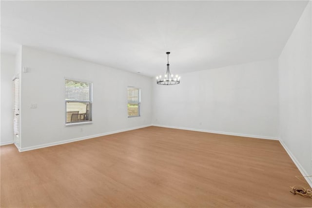 empty room with a notable chandelier and light hardwood / wood-style flooring