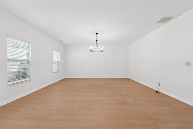 empty room featuring light hardwood / wood-style flooring and an inviting chandelier