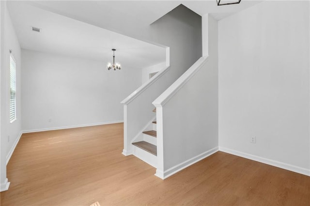 staircase with hardwood / wood-style floors and an inviting chandelier