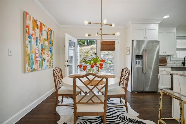 dining area featuring a notable chandelier, dark hardwood / wood-style floors, ornamental molding, and sink