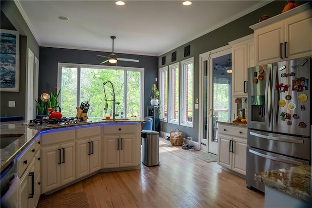 kitchen featuring light wood-style floors, a wealth of natural light, a ceiling fan, a sink, and stainless steel appliances
