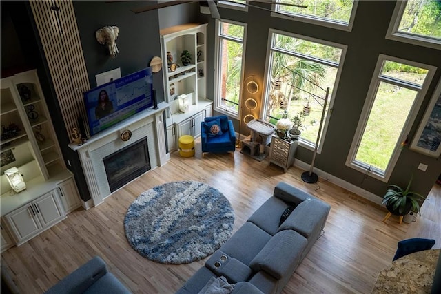 living room with baseboards, wood finished floors, and a glass covered fireplace