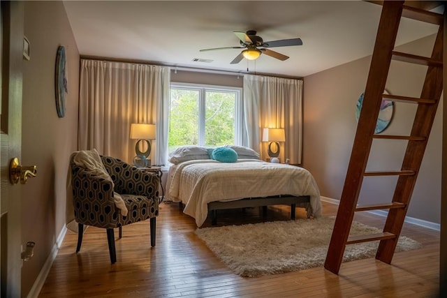 bedroom featuring visible vents, hardwood / wood-style flooring, baseboards, and a ceiling fan