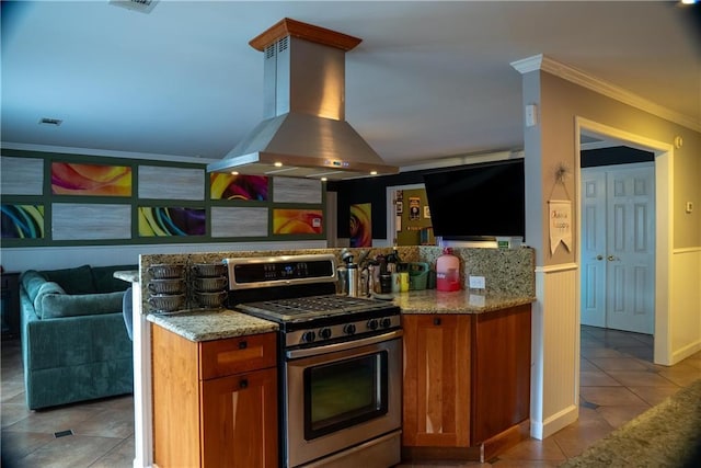 kitchen featuring light tile patterned floors, stainless steel gas range, crown molding, brown cabinetry, and island exhaust hood
