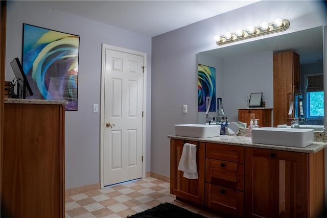 full bathroom featuring a sink, tile patterned floors, double vanity, and baseboards