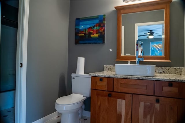 bathroom with vanity, baseboards, toilet, and ceiling fan