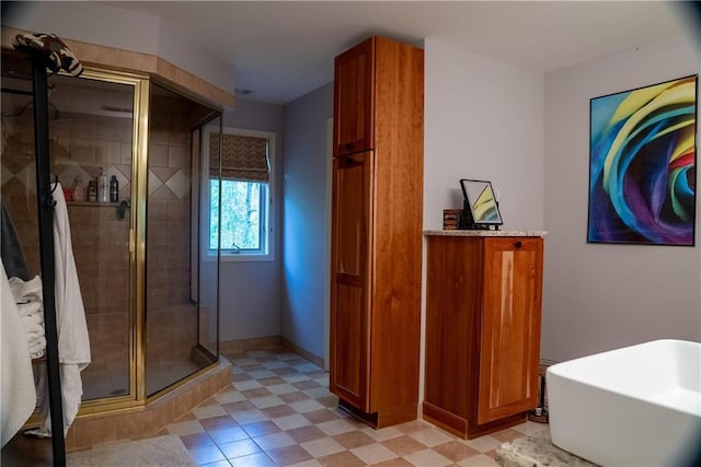 bathroom with a shower stall, a freestanding tub, and baseboards