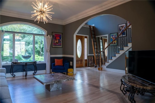 living area featuring baseboards, arched walkways, a notable chandelier, and wood finished floors