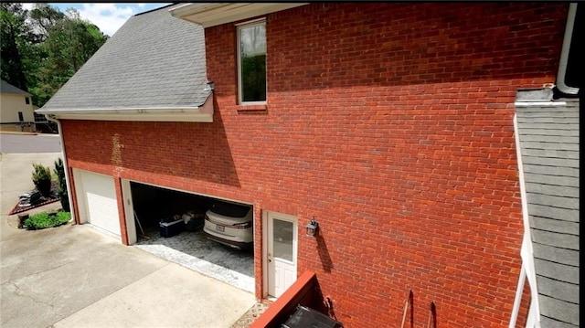 view of side of property with an attached garage, driveway, and brick siding