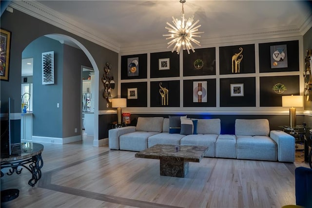 living room with a notable chandelier, baseboards, crown molding, arched walkways, and wood finished floors