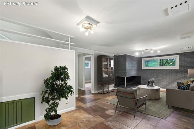 living area with baseboards and brick wall