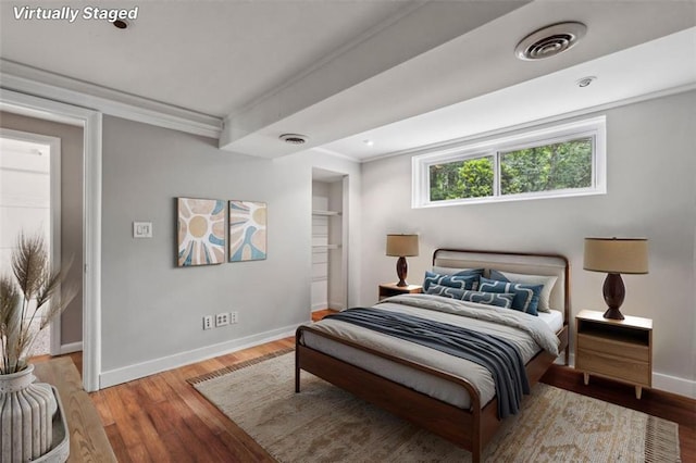 bedroom featuring baseboards, wood finished floors, and crown molding