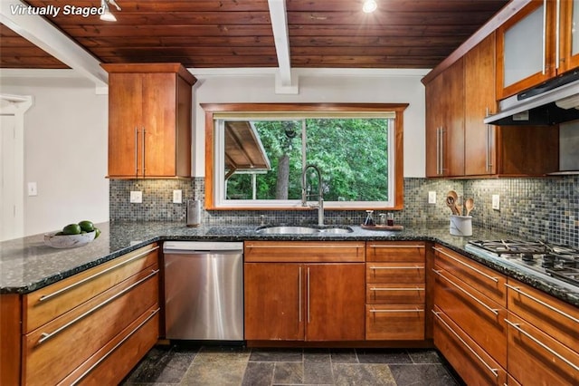 kitchen featuring appliances with stainless steel finishes, a sink, wooden ceiling, under cabinet range hood, and dark stone counters