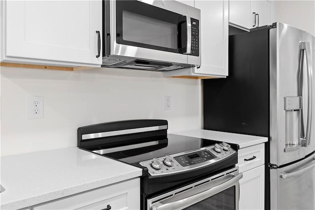 kitchen with light stone counters, white cabinets, and appliances with stainless steel finishes