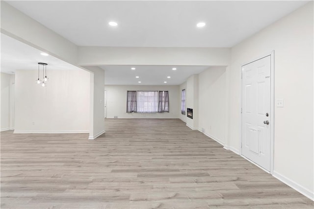 unfurnished living room featuring light wood-type flooring and a notable chandelier