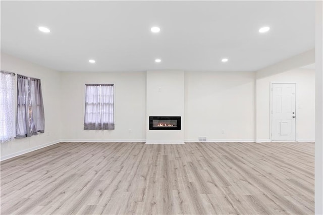 unfurnished living room with light hardwood / wood-style floors and heating unit