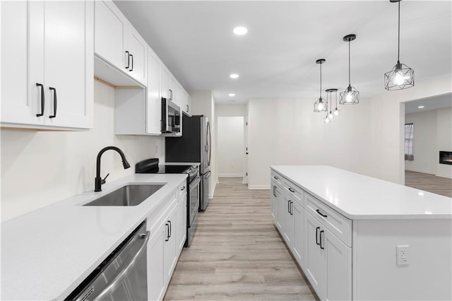 kitchen featuring pendant lighting, white cabinets, stainless steel appliances, light hardwood / wood-style floors, and sink