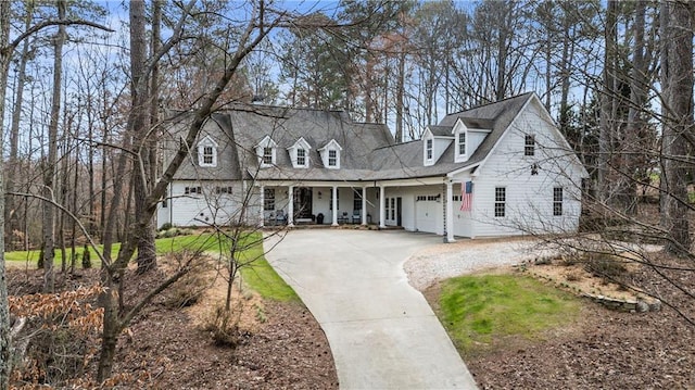 cape cod home with a porch, concrete driveway, and a garage