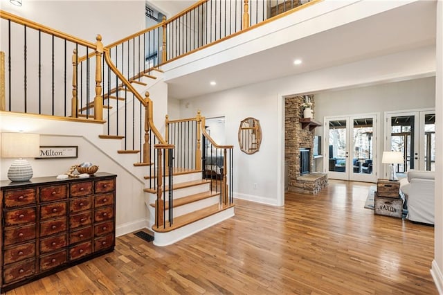 stairway featuring baseboards, wood finished floors, a high ceiling, french doors, and recessed lighting