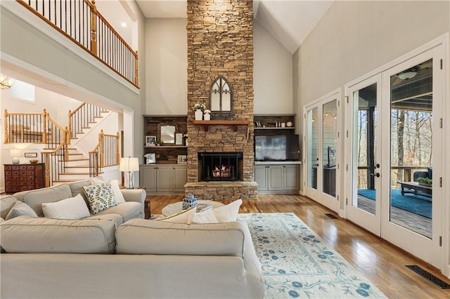 living room featuring visible vents, stairway, wood finished floors, french doors, and a fireplace