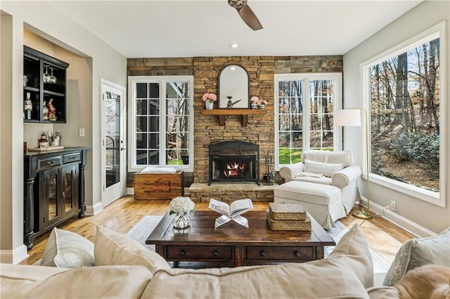 sunroom / solarium featuring ceiling fan, a dry bar, a fireplace, and a healthy amount of sunlight