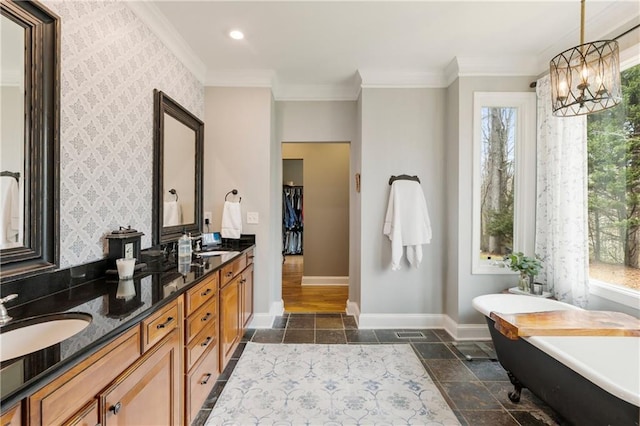 bathroom featuring wallpapered walls, a healthy amount of sunlight, a sink, and baseboards