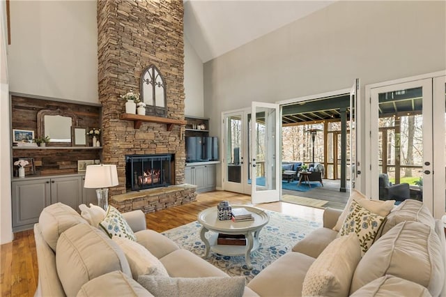 living room featuring high vaulted ceiling, french doors, a fireplace, and wood finished floors