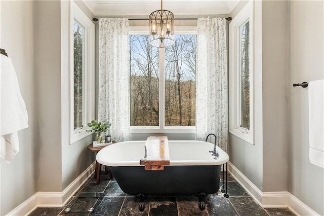 bathroom with a freestanding bath, marble finish floor, a notable chandelier, and baseboards