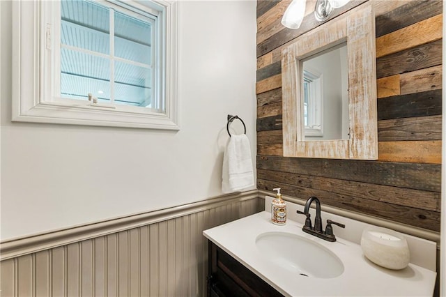 bathroom with a wainscoted wall, wood walls, and vanity