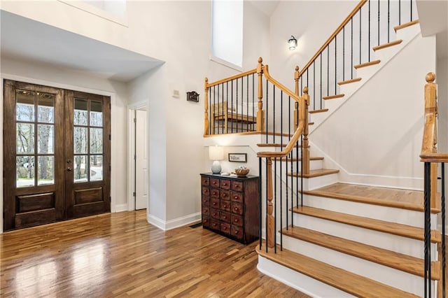 entrance foyer with french doors, stairway, baseboards, and wood finished floors