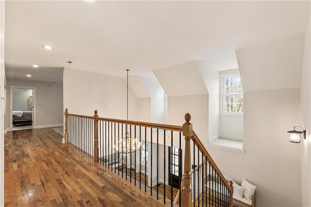 hallway featuring visible vents, an upstairs landing, vaulted ceiling, baseboards, and hardwood / wood-style floors