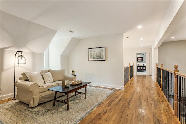 living room featuring baseboards, visible vents, lofted ceiling, hardwood / wood-style floors, and recessed lighting