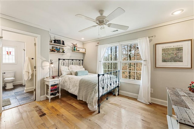 bedroom featuring light wood finished floors, visible vents, ensuite bathroom, ceiling fan, and baseboards