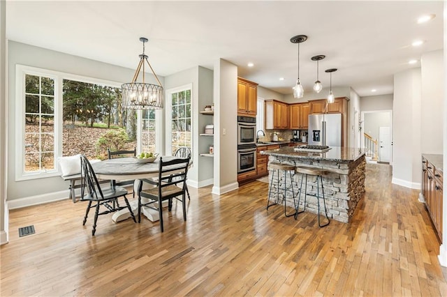 kitchen with light wood-style flooring, a sink, visible vents, appliances with stainless steel finishes, and brown cabinets