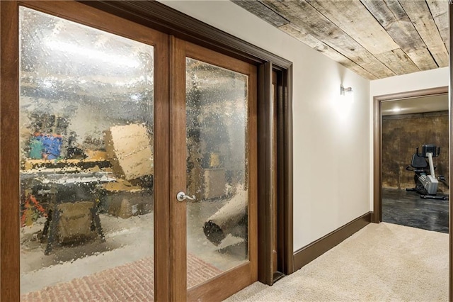 hall featuring carpet floors, wood ceiling, and baseboards