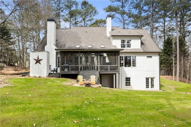 rear view of house featuring an outdoor fire pit, a storage shed, a sunroom, a lawn, and a chimney