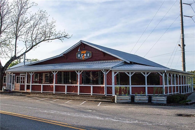 exterior space with uncovered parking, covered porch, and metal roof