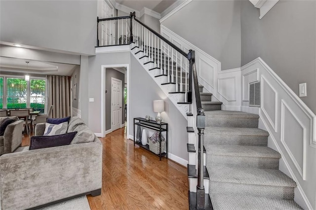 stairway with hardwood / wood-style flooring, crown molding, and a high ceiling