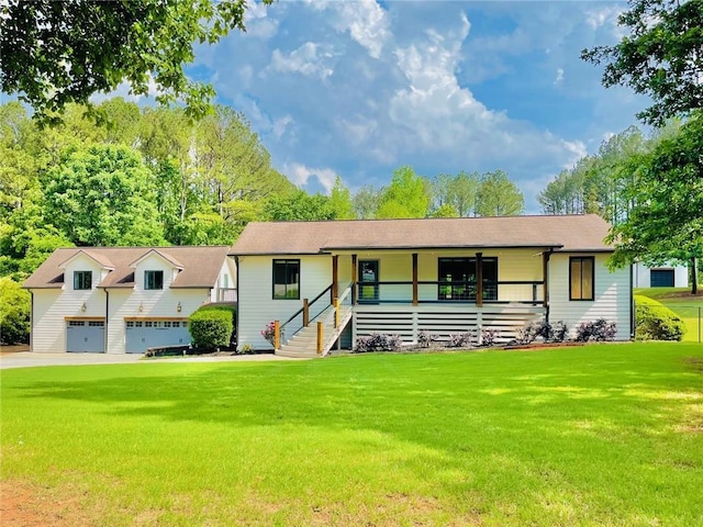 view of front of house featuring covered porch, a front yard, and a detached garage