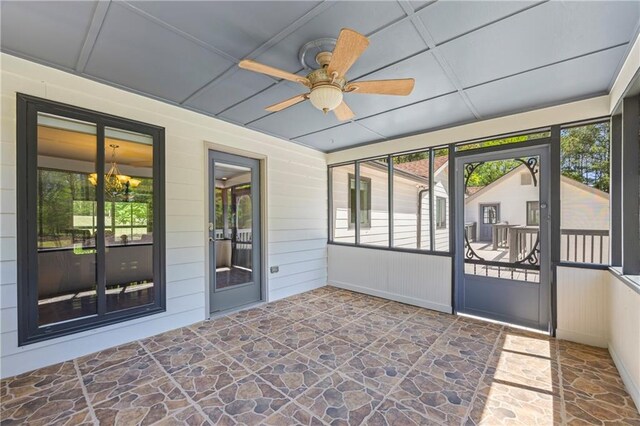 unfurnished sunroom featuring ceiling fan with notable chandelier