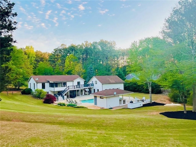 rear view of property with an outdoor structure, an outdoor pool, a yard, and a deck