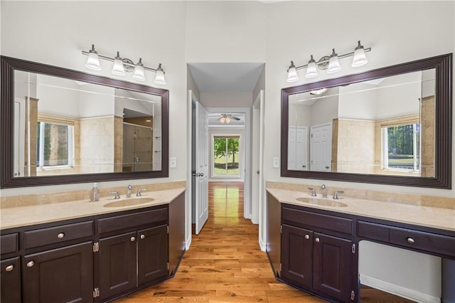 bathroom featuring vanity, wood finished floors, a wealth of natural light, and tiled shower