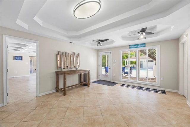 entrance foyer featuring a ceiling fan, light tile patterned floors, and a raised ceiling