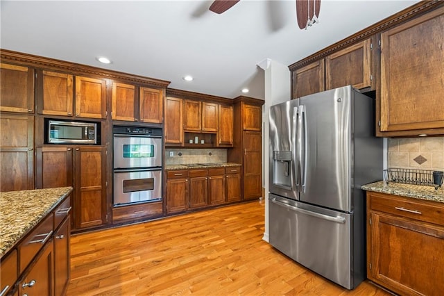 kitchen featuring decorative backsplash, ceiling fan, light stone counters, stainless steel appliances, and recessed lighting