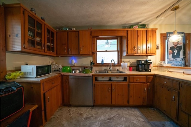 kitchen with a textured ceiling, decorative light fixtures, stainless steel dishwasher, and sink