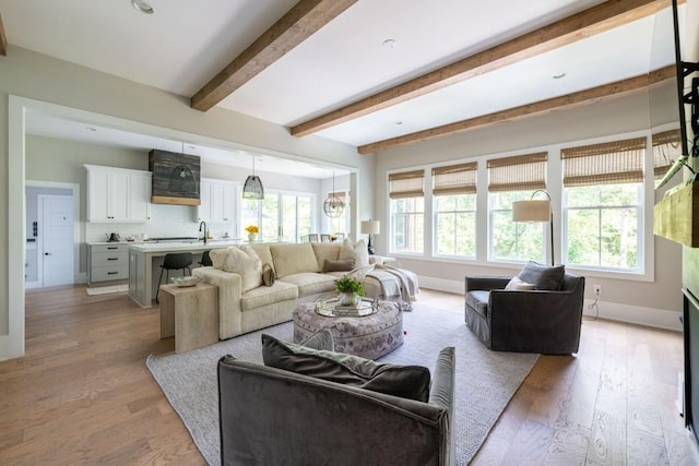 living room with baseboards, beam ceiling, and light wood-type flooring