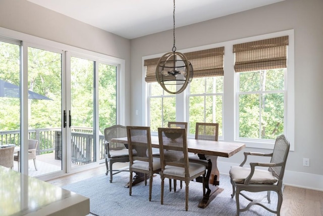 dining area featuring baseboards, wood finished floors, and a notable chandelier