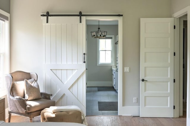 interior space featuring baseboards, a barn door, light wood finished floors, and a chandelier