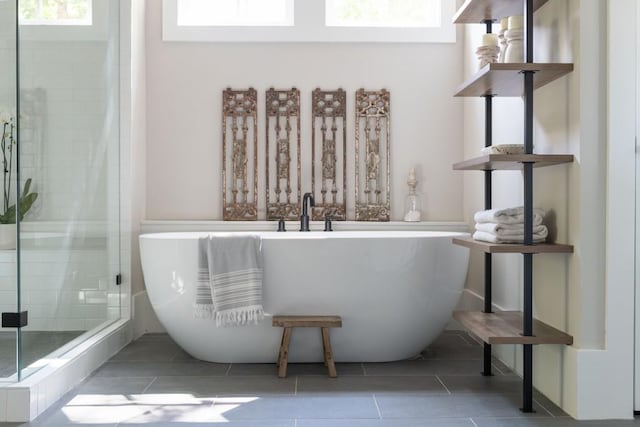 bathroom with tile patterned flooring, a freestanding bath, and a stall shower